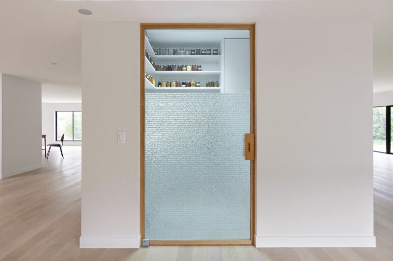 A pantry door with textured ornamental glass in a white oak frame.