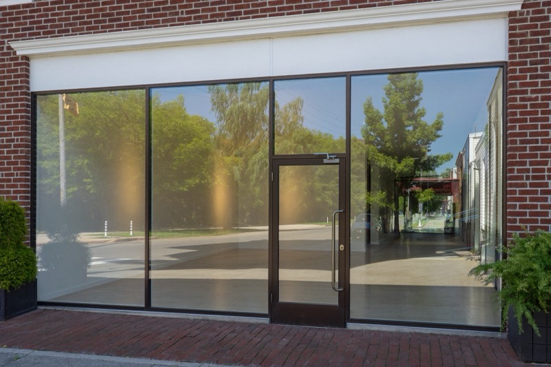 Tall clear storefront glass in slim bronze frames on a red brick facade.